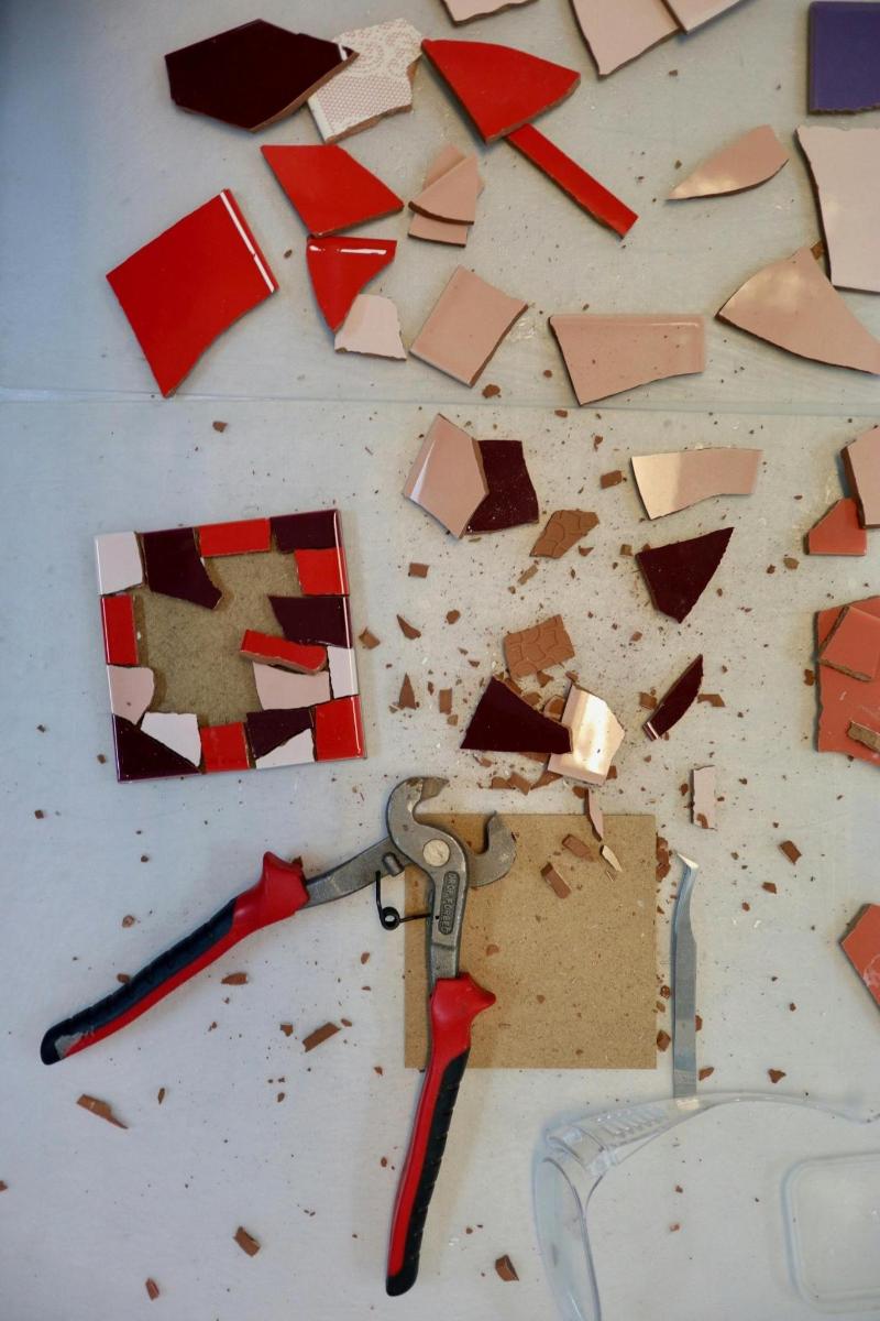 a table with broken tiles and a pair of scissors