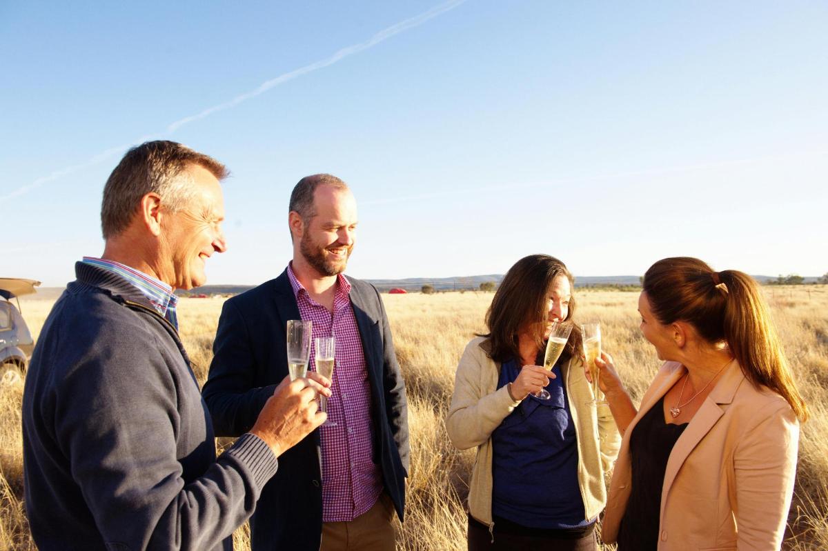 a group of people standing in a field holding champagne glasses
