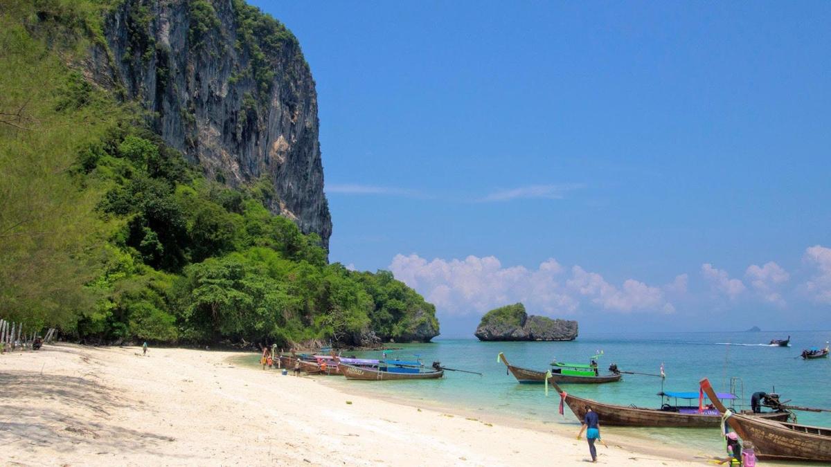 pantai dengan bot di atas air dan gunung