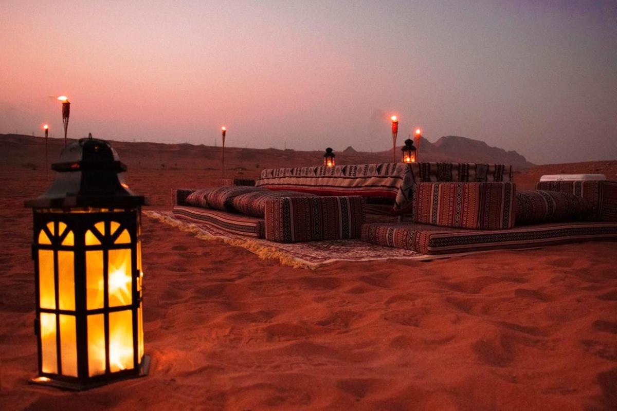 eine Reihe von Decken in der Wüste mit einer Laterne im Sand