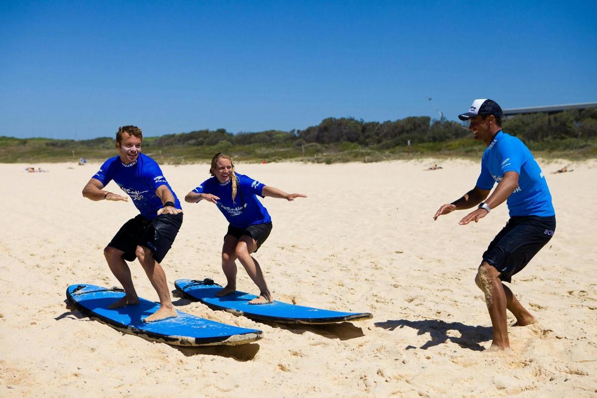 un grup de persones sobre taules de surf a la platja