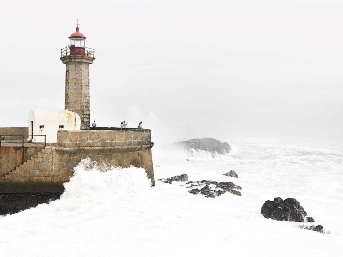 um farol coberto de neve próximo ao oceano