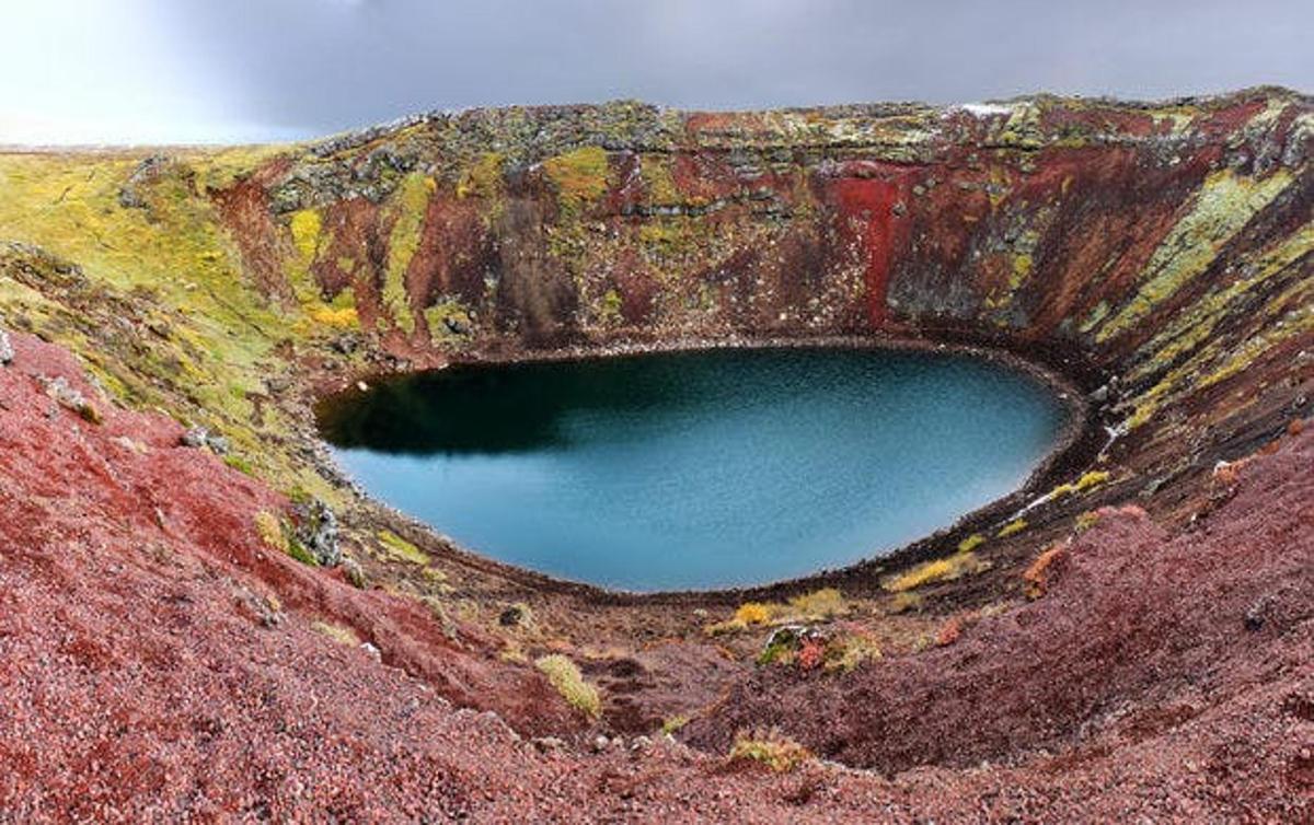Un agujero en la ladera de una montaña con un lago azul