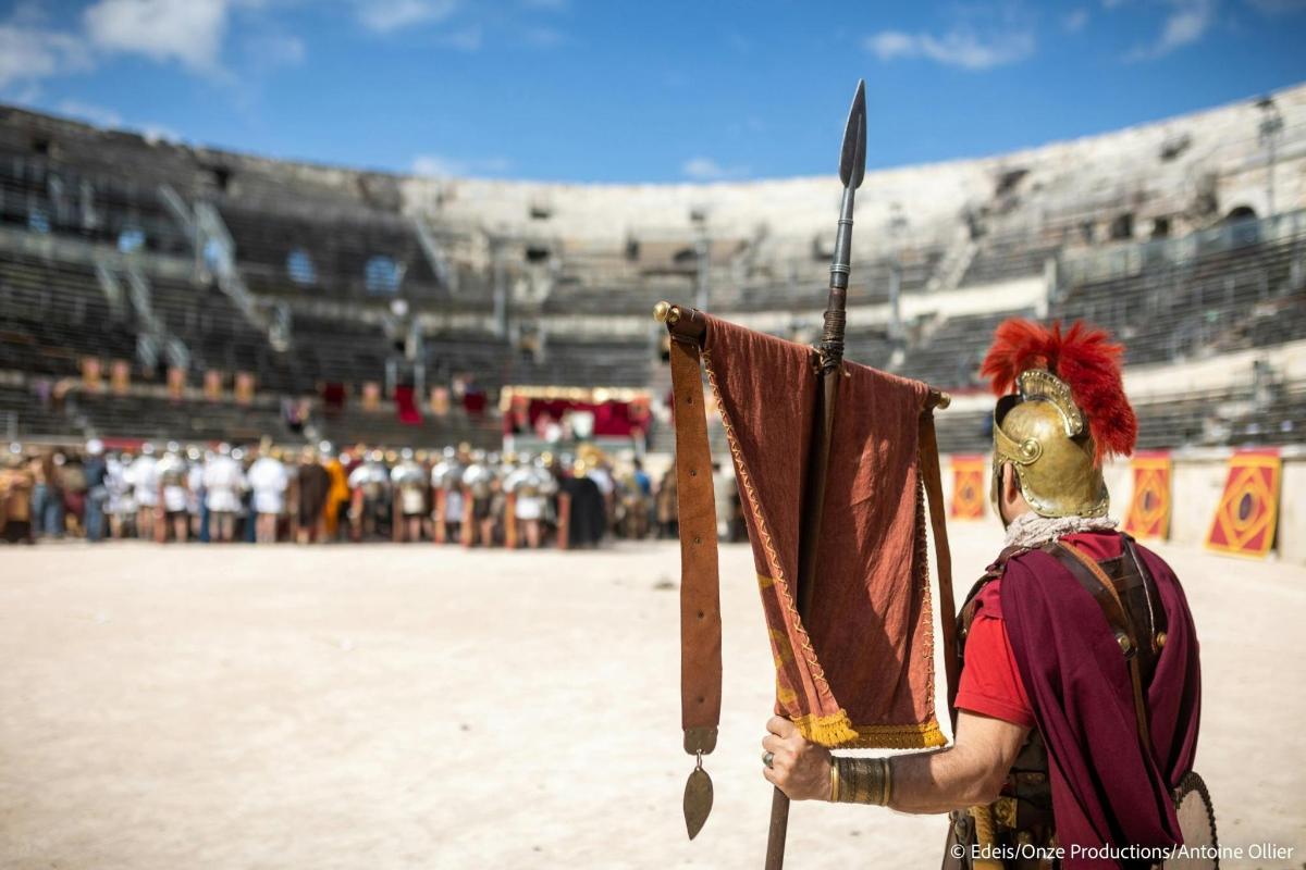 a man holding a spear in front of a stadium