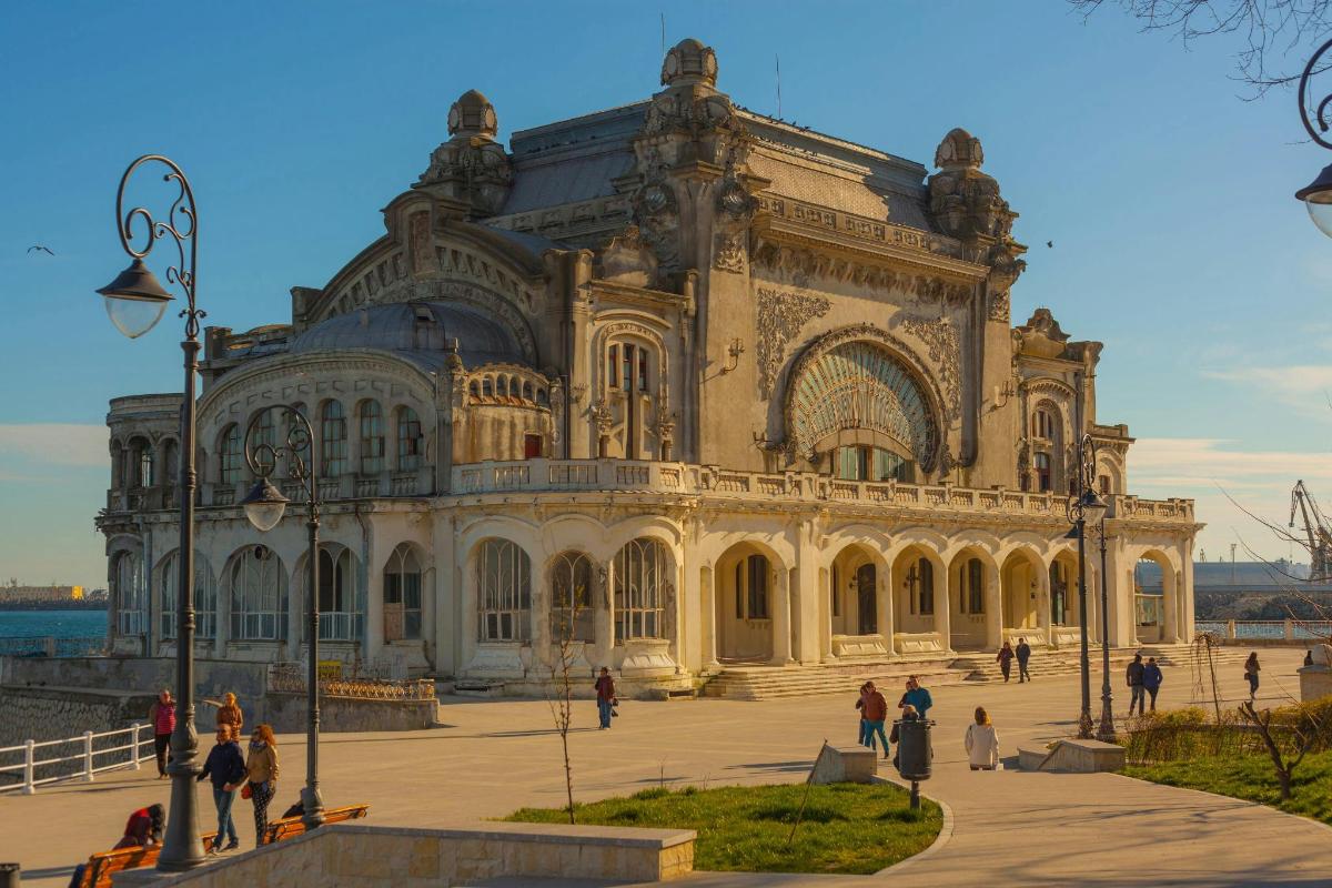o clădire mare prin fața căreia se plimbă oameni