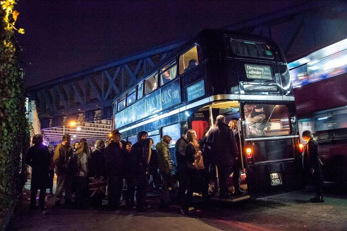 un grup de oameni care stau în fața unui autobuz cu etaj