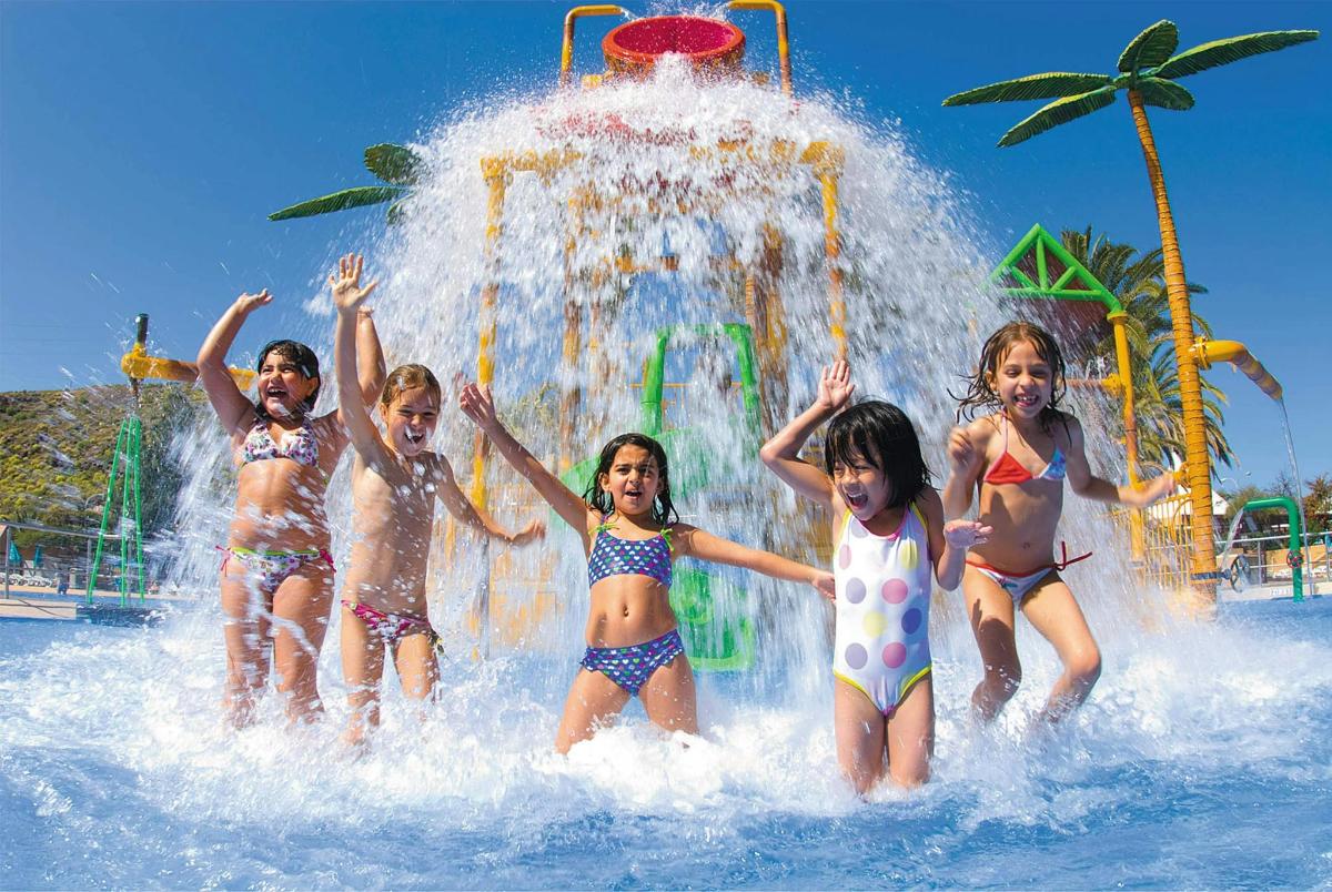 a group of children playing in a fountain at a water park