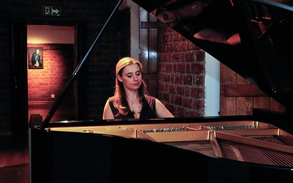a woman sitting at a piano in front of a mirror