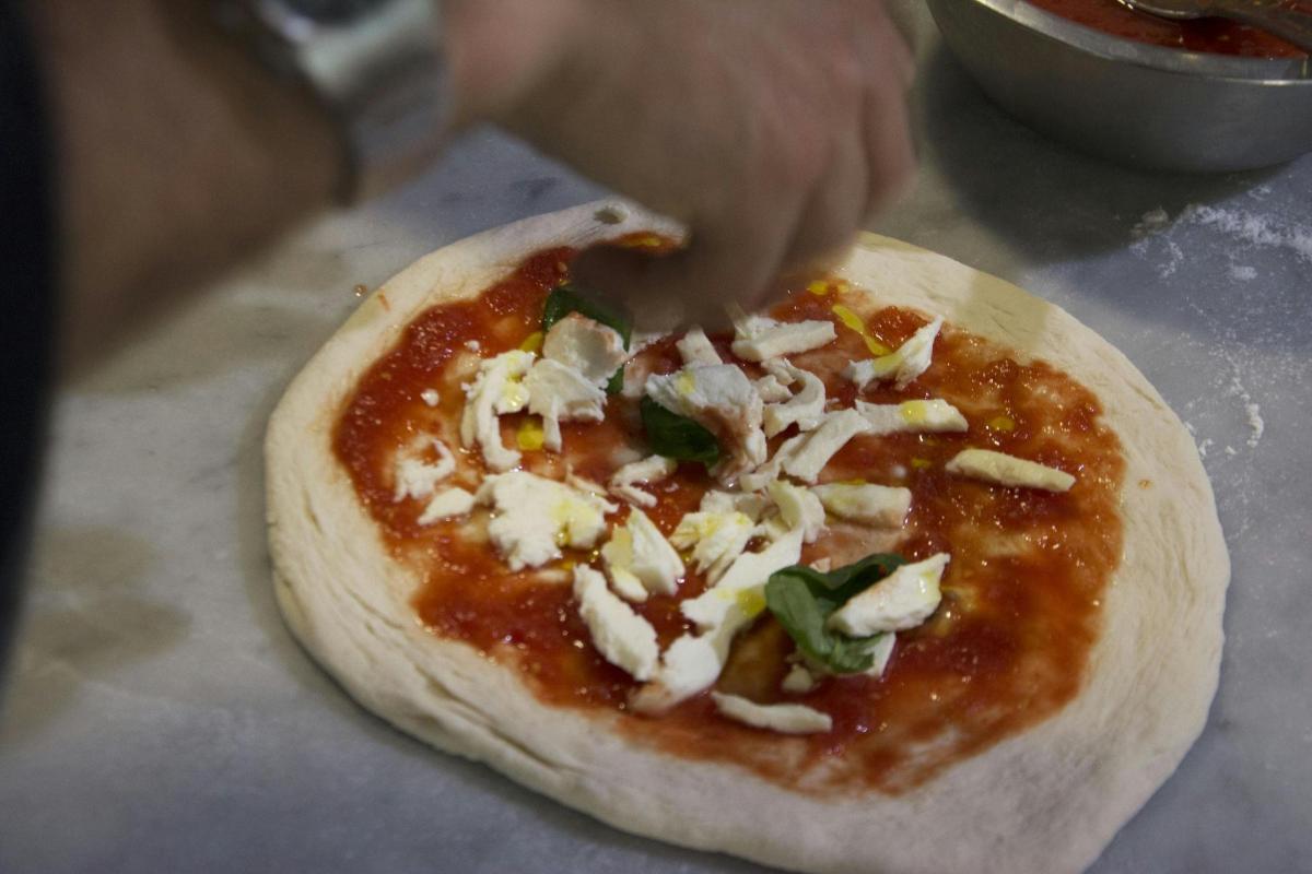 člověk přidává polevu na pizzu