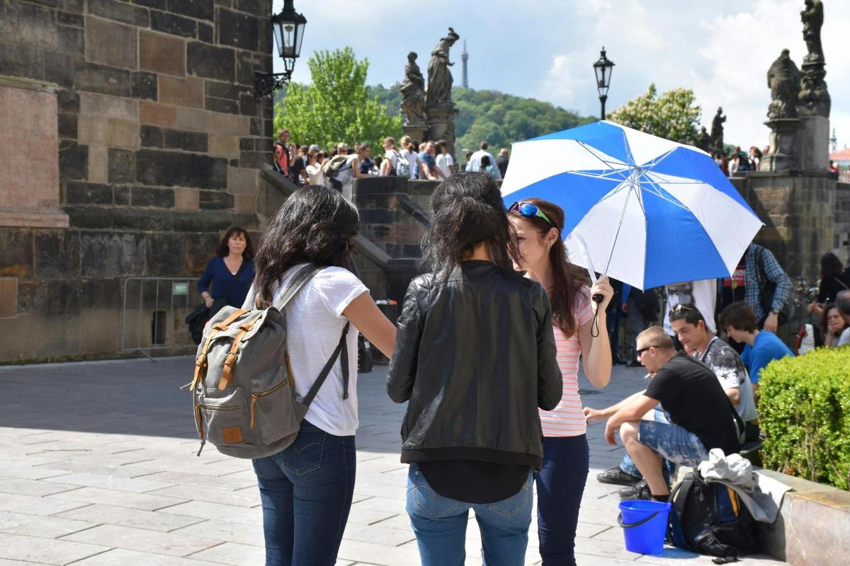 a group of three women walking down a street with an umbrella