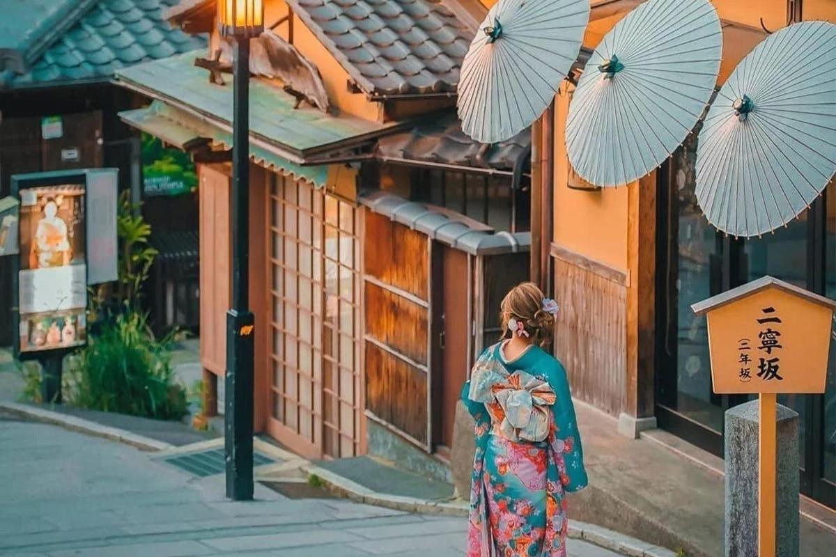 Una mujer con un vestido caminando por una calle con paraguas.