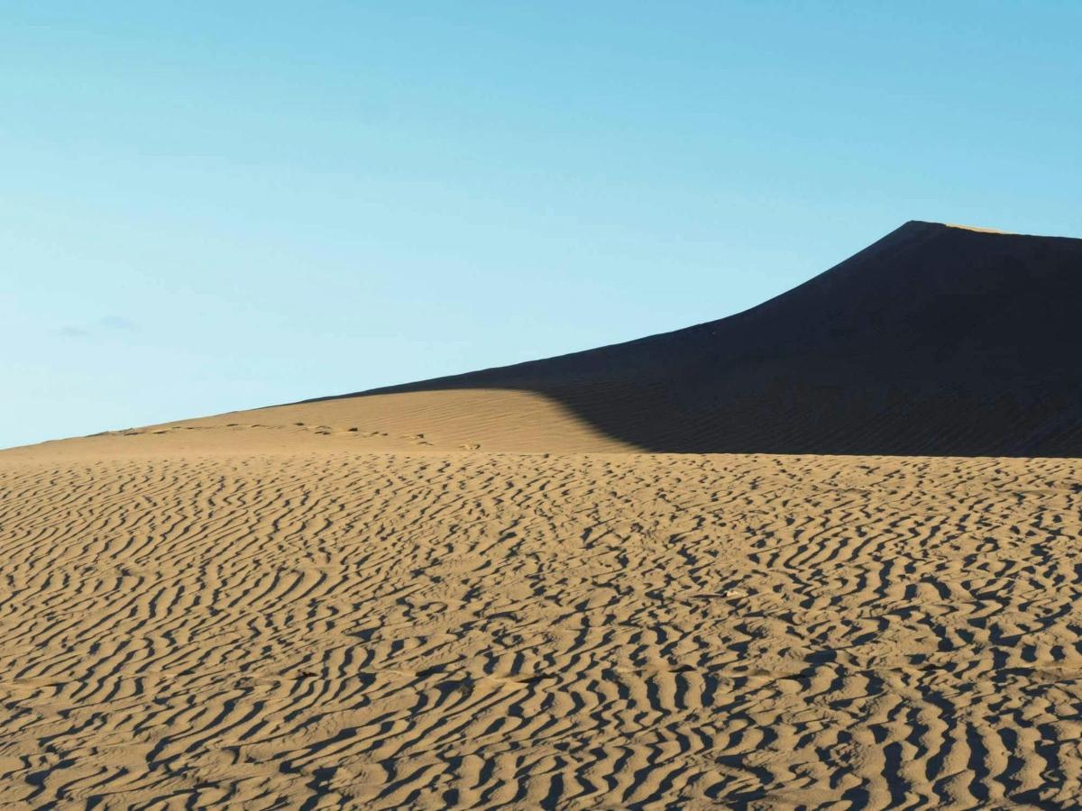a sand dune with a mountain in the background