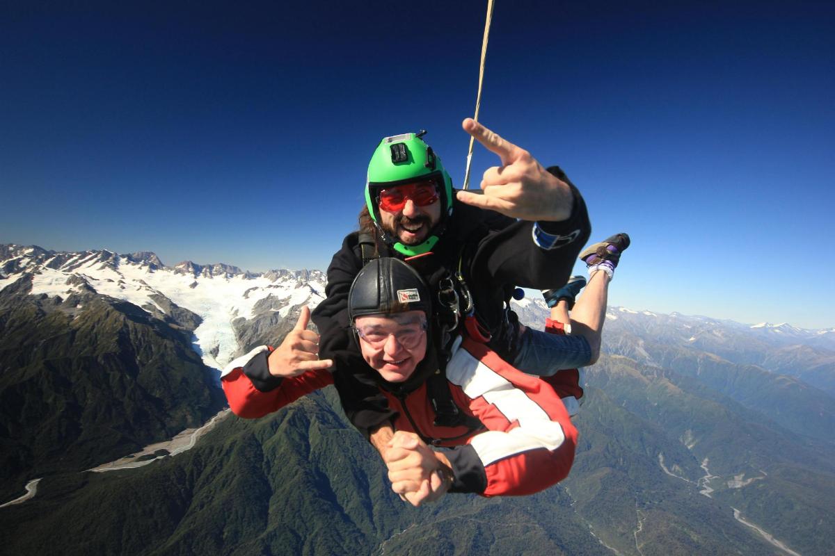 Dos hombres están haciendo tirolesa en la cima de una montaña