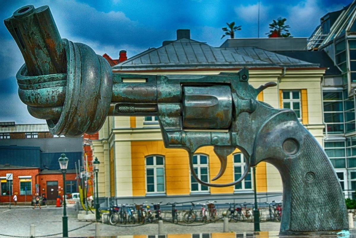 Una estatua de pistola de metal frente a un edificio