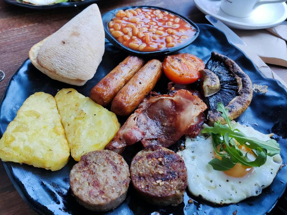 um prato azul de comida com salsicha, ovos, batatas e feijão