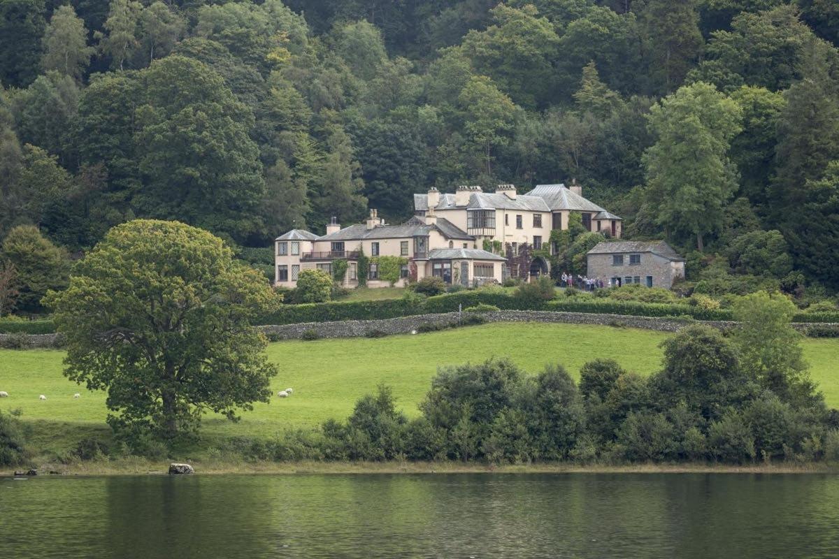 een groot huis op een heuvel naast een meer