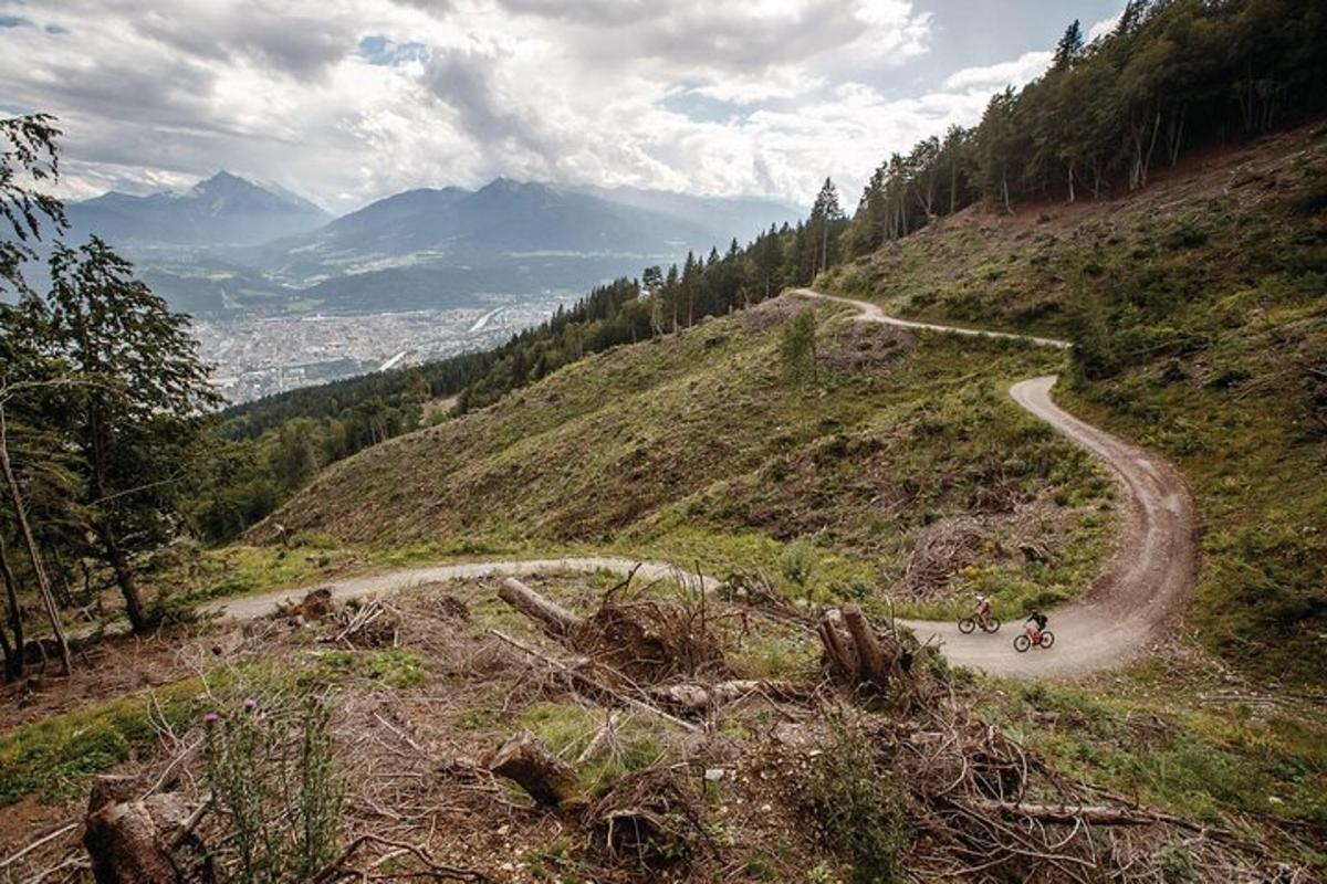 zwei Personen fahren mit dem Fahrrad eine unbefestigte Straße auf einem Hügel hinunter