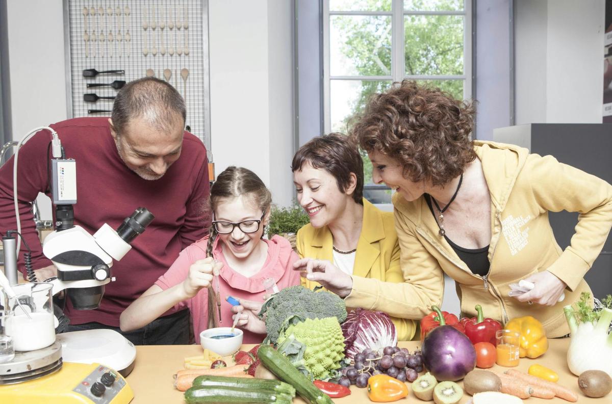 a group of people standing around a table with vegetables