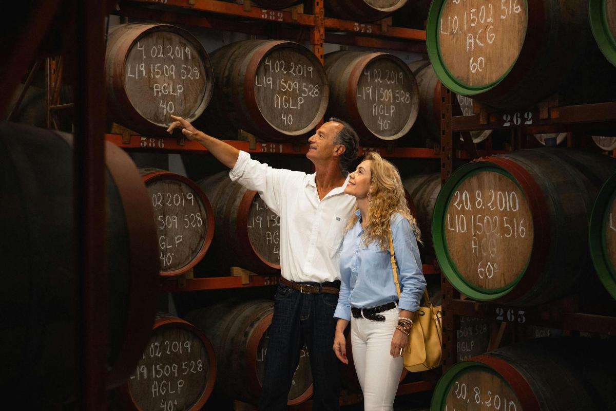 un uomo e una donna in piedi davanti a un muro di botti di vino