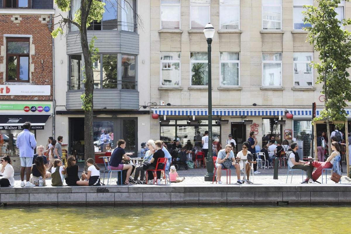 μια ομάδα ανθρώπων που κάθονται σε τραπέζια κοντά σε ένα ποτάμι
