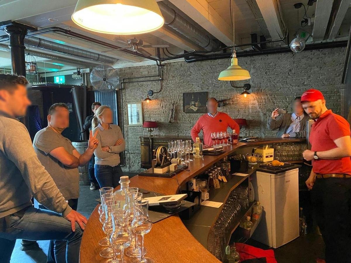 a group of people standing around a bar with wine glasses