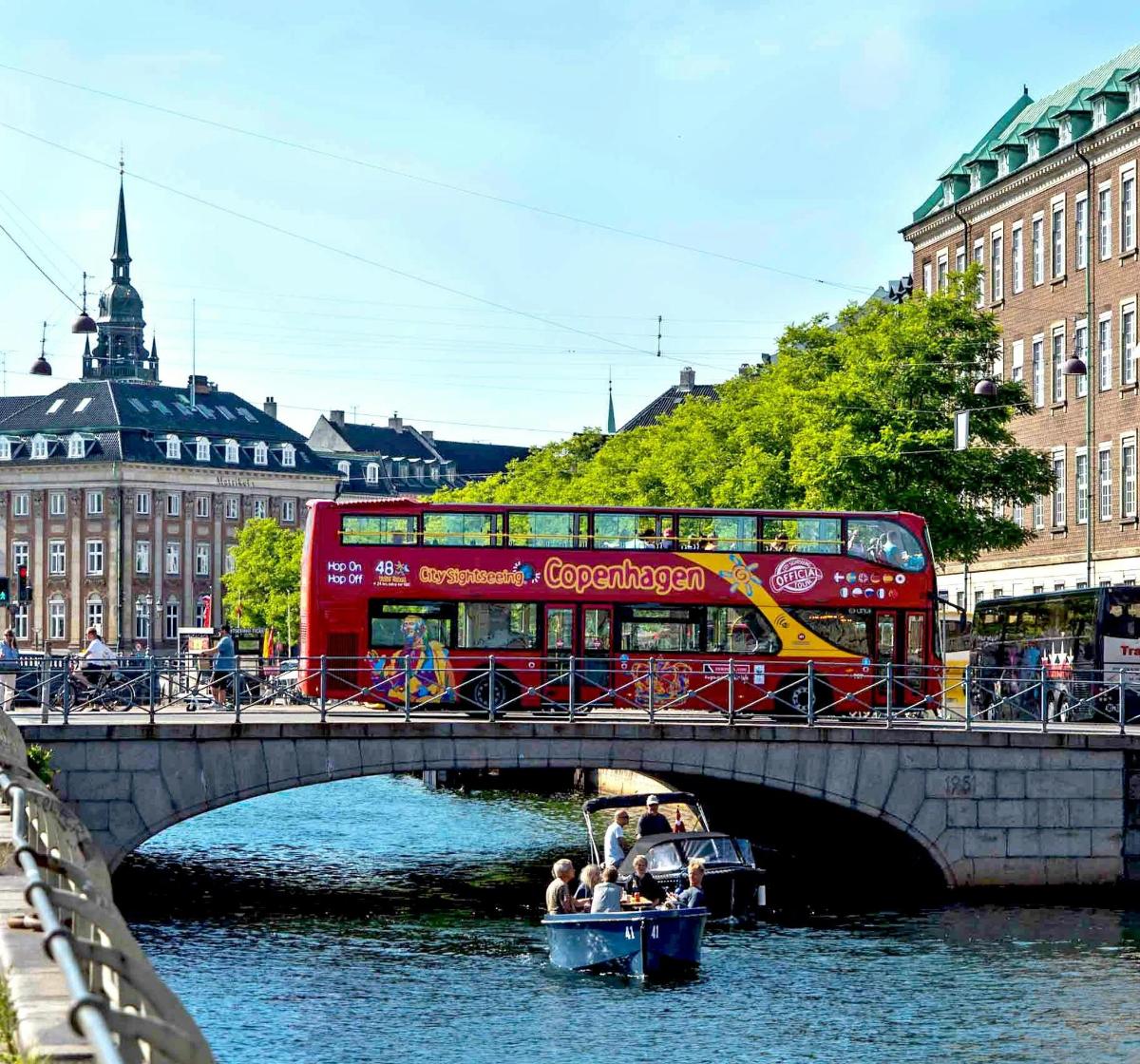 Červený dvoupatrový autobus na mostě s lodí