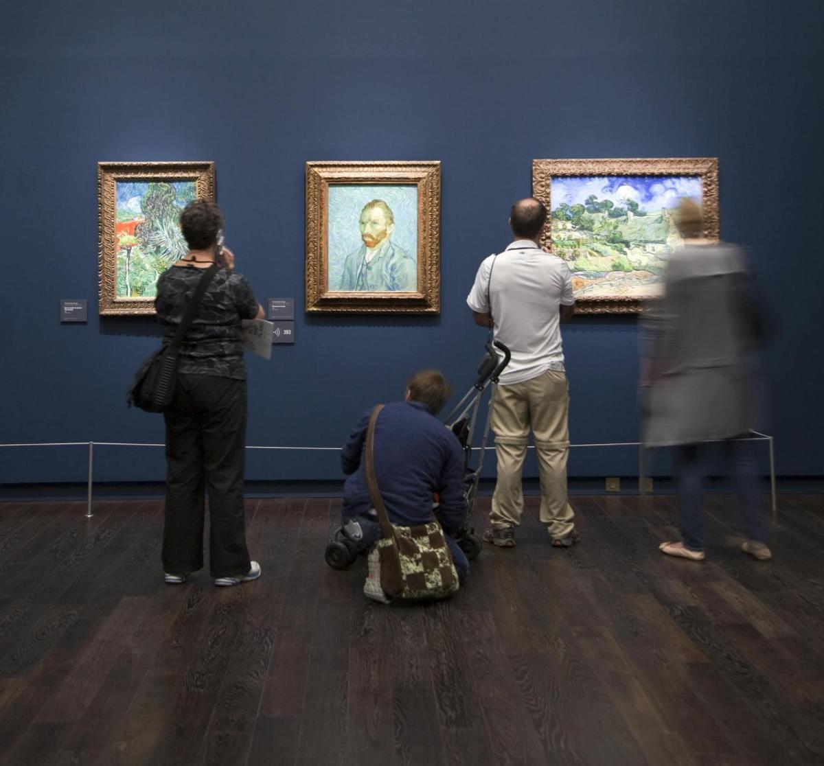 un groupe de personnes regardant des peintures dans un musée