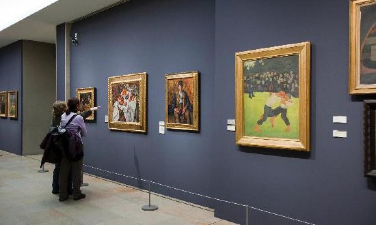 un groupe de personnes regardant des peintures dans un musée