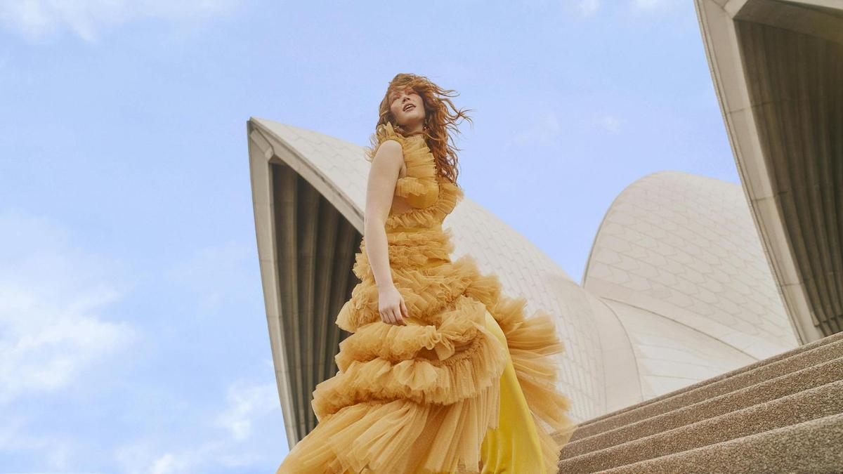 une femme en robe jaune debout sur des escaliers