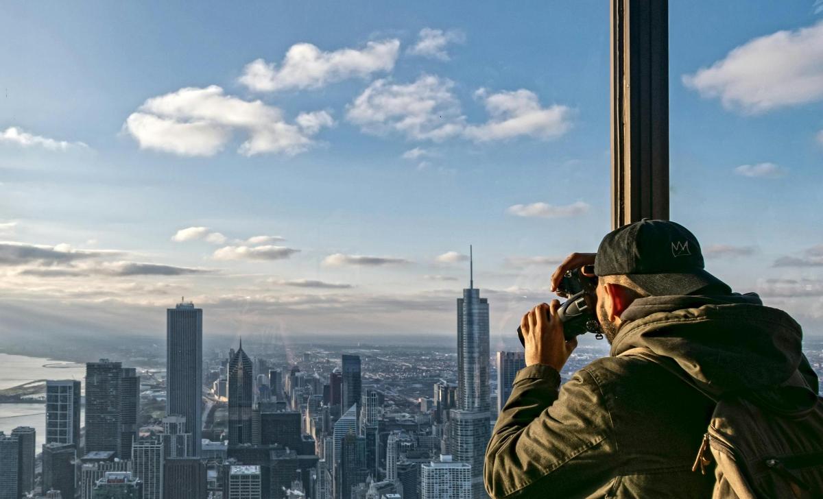 Un hombre tomando una fotografía de una ciudad desde una torre.