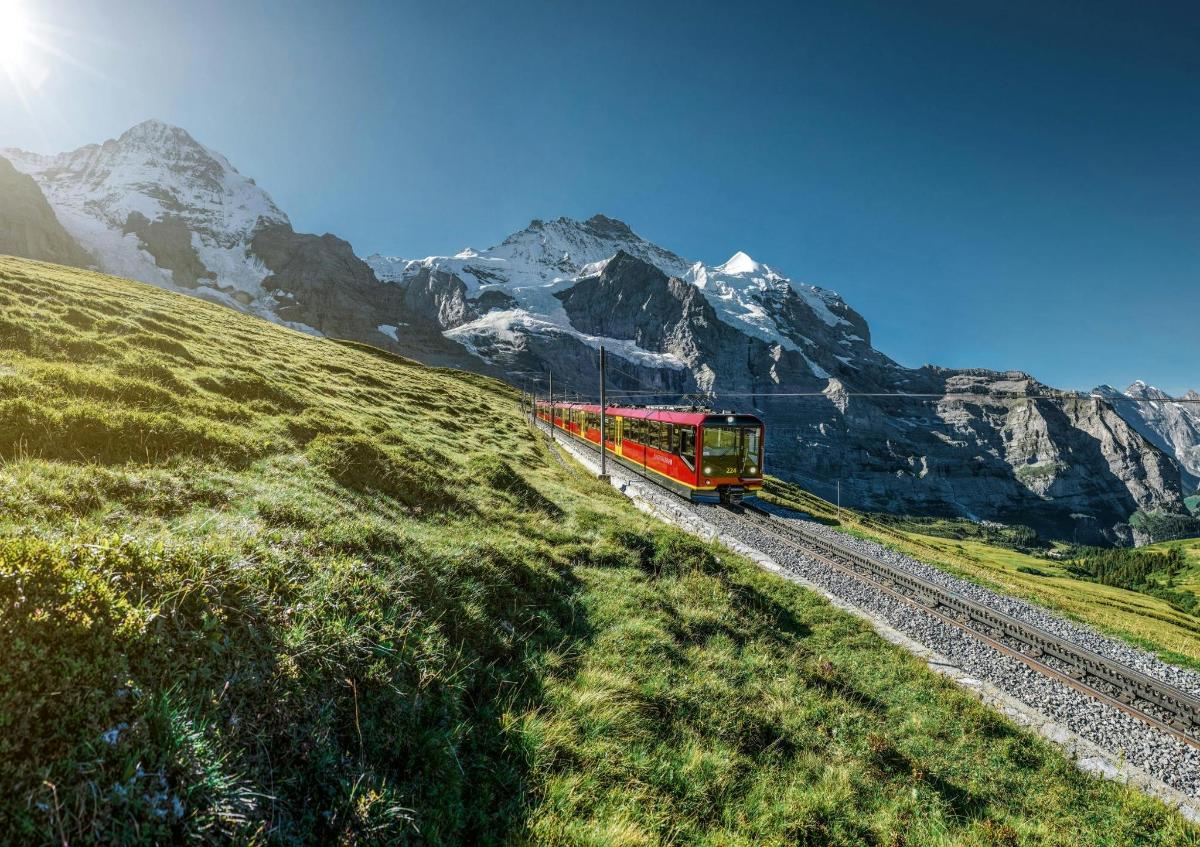 a red train traveling down the tracks in the mountains