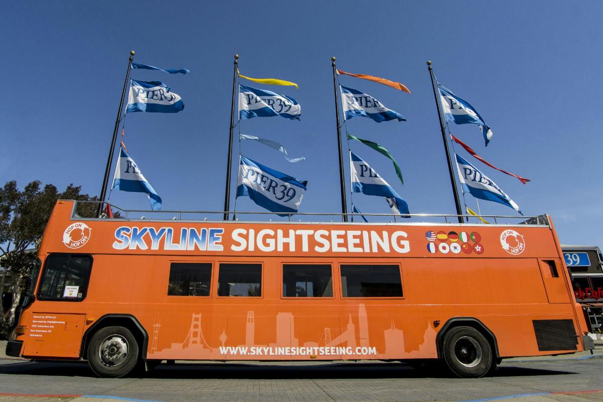 oranžový autobus s vlajkami na boku