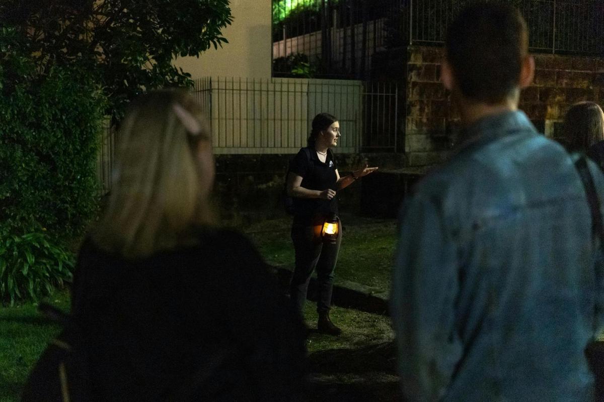žena stojící v noci před skupinou lidí