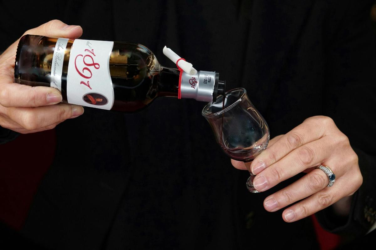 a person pouring a bottle of wine into a glass