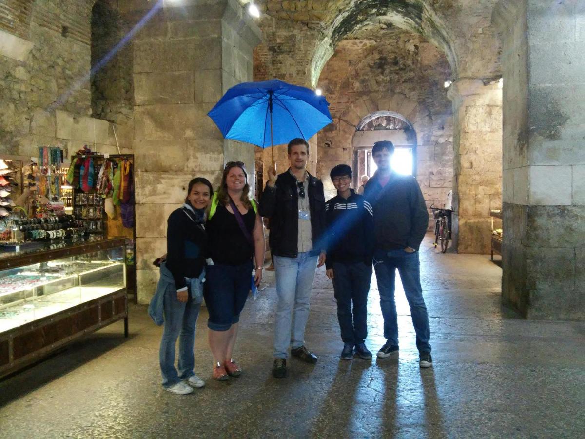 eine Gruppe von Menschen steht unter einem blauen Regenschirm