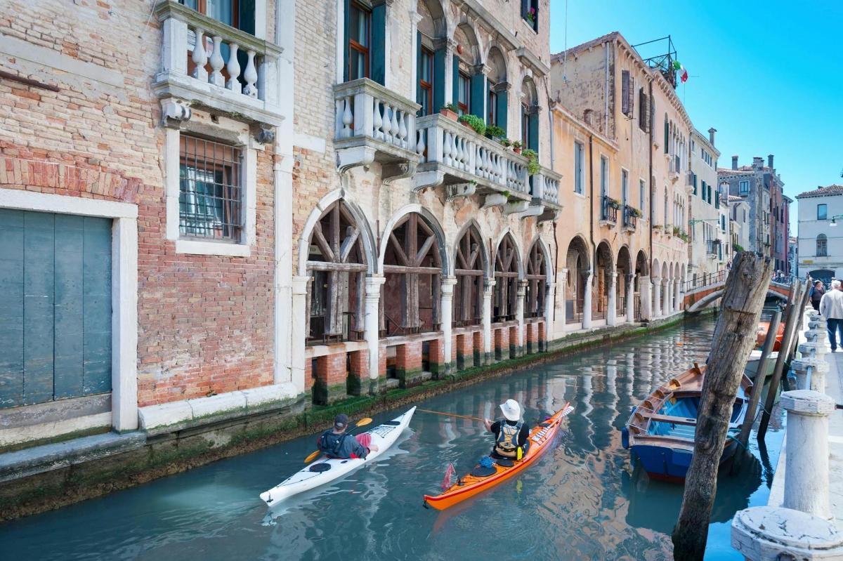 two people in kayaks on a canal in a city