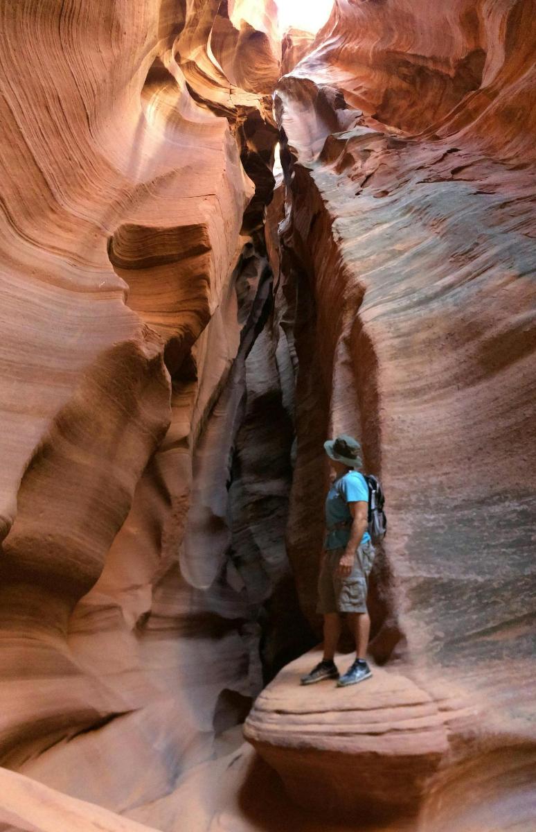 a man standing on a rock in a slot canyon