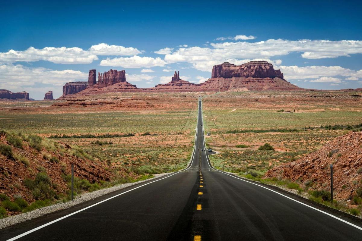 an empty road in the desert with red rocks