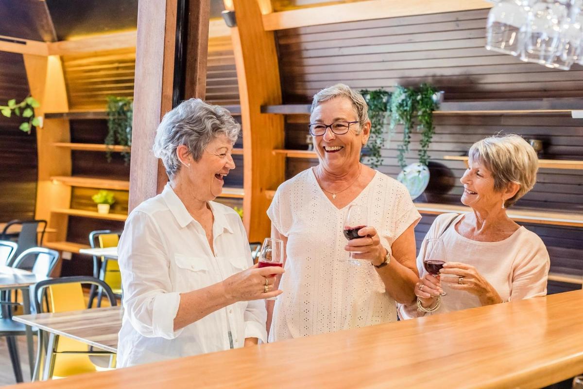 three older women standing around a table holding wine glasses