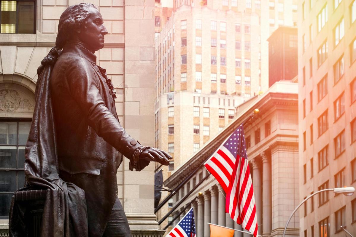 una statua di un uomo in piedi davanti a un edificio con bandiere americane