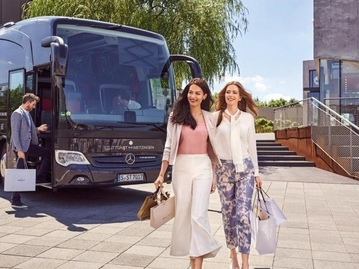 two women are standing in front of a bus