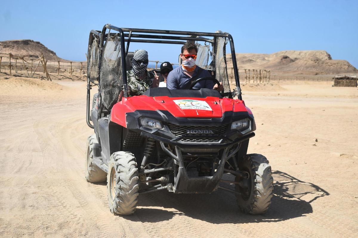 seorang pria mengendarai ATV merah di padang pasir