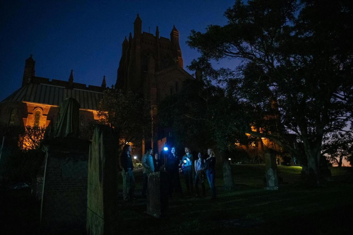 um grupo de pessoas em pé em frente a uma igreja à noite