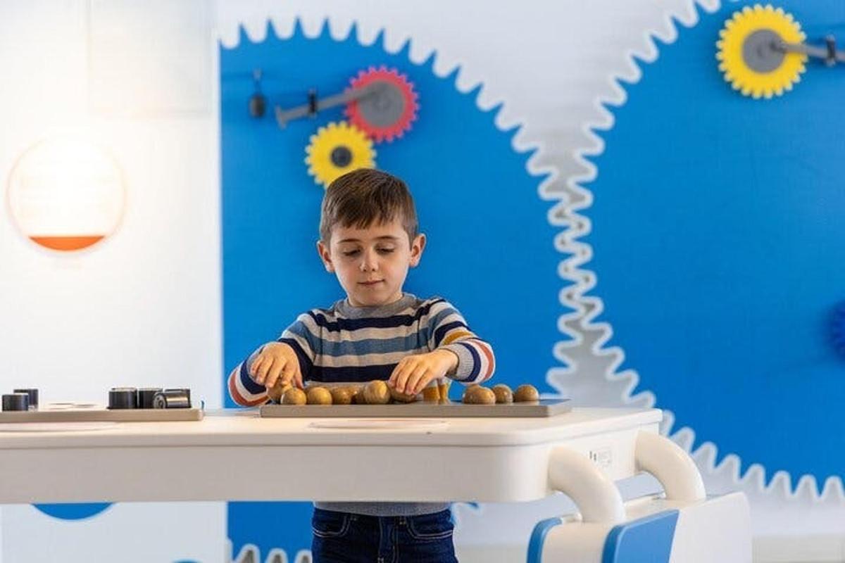a young boy sitting at a table with balls