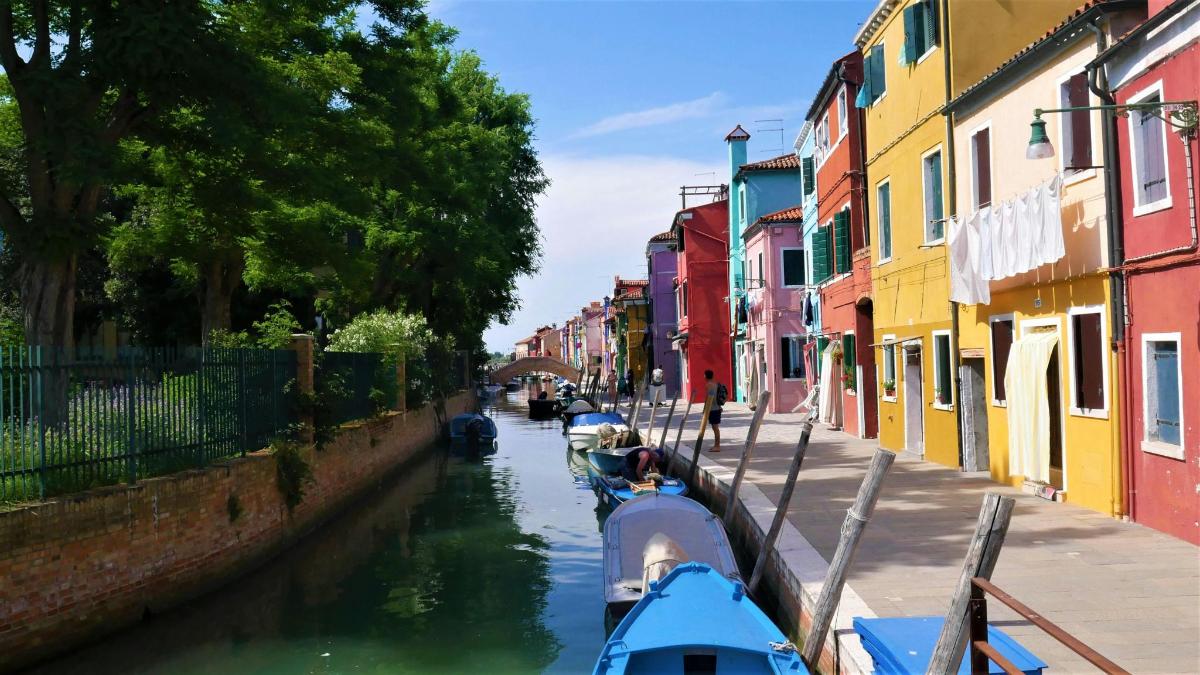 two boats are docked on a canal with colorful buildings
