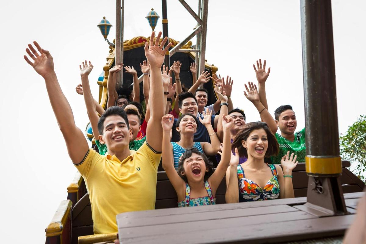 a group of people on a roller coaster with their hands in the air