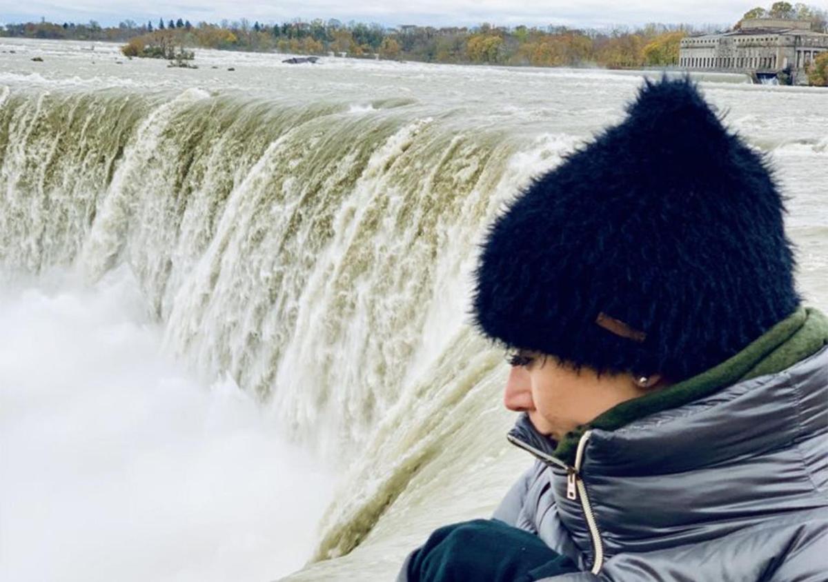 a man in a hat in front of a waterfall