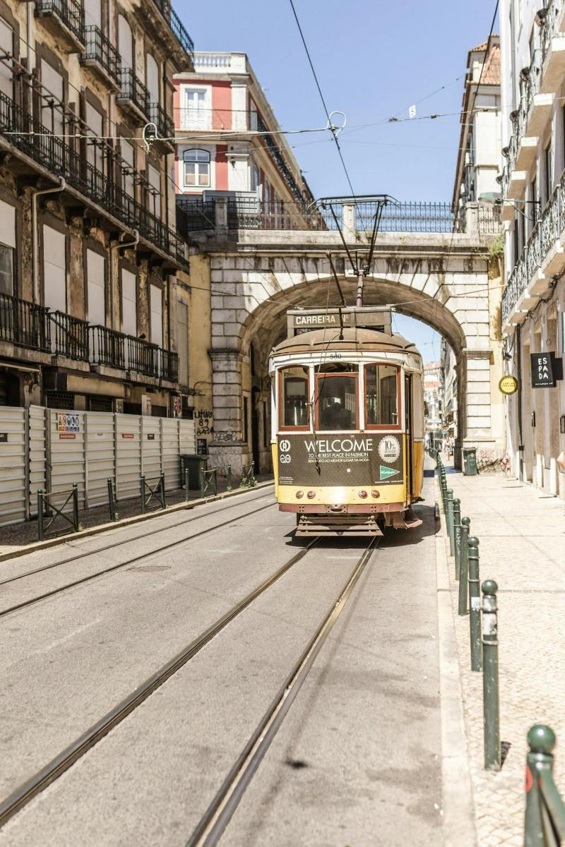 a trolley car driving down a street under a bridge