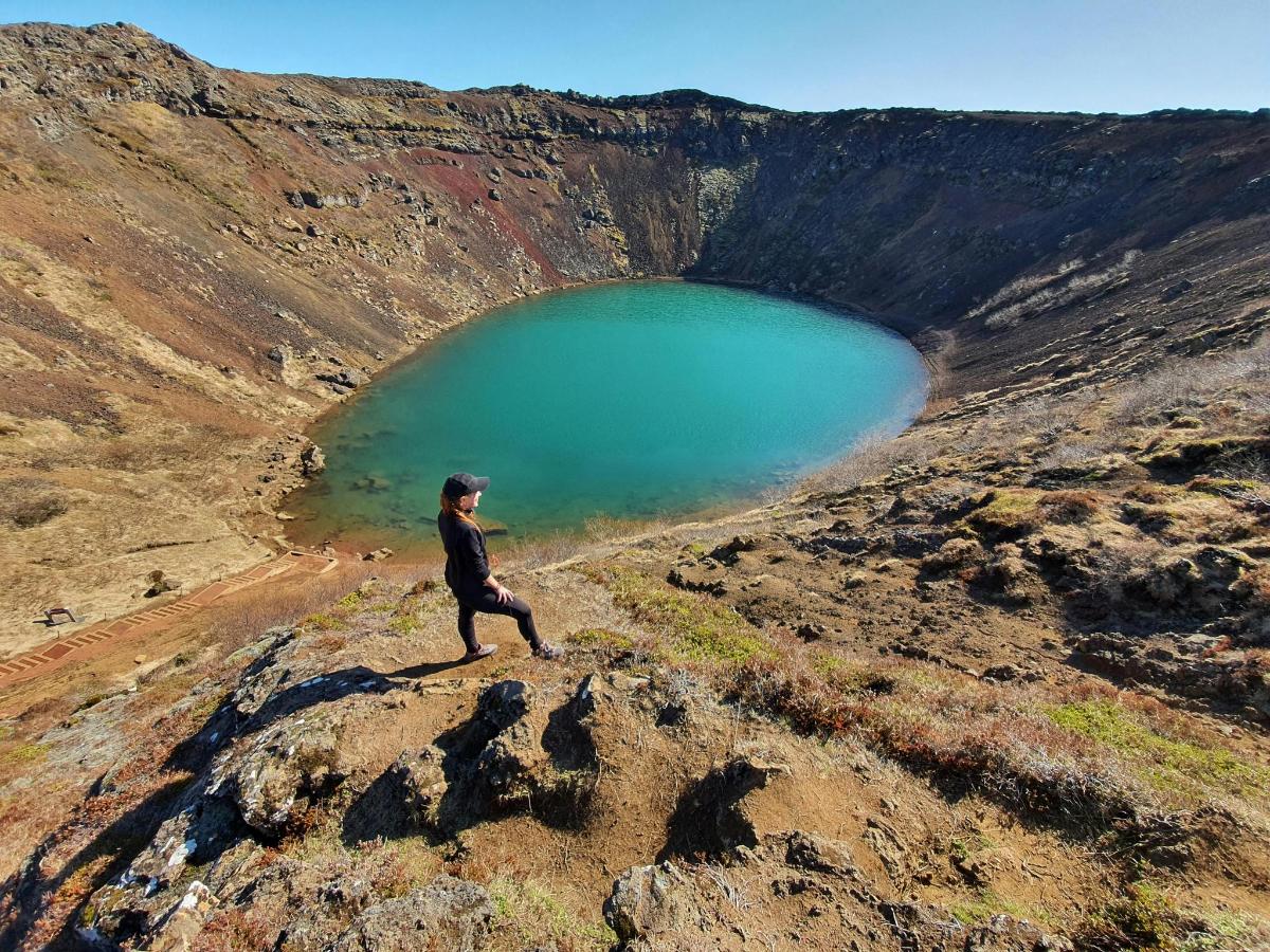 en person som går på toppen av et fjell nær en innsjø