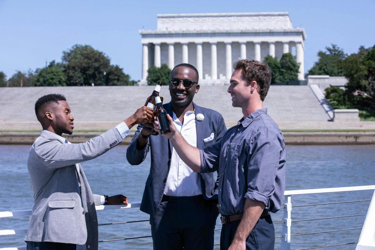 Egy férfi két férfit fényképez a Washington-emlékmű előtt